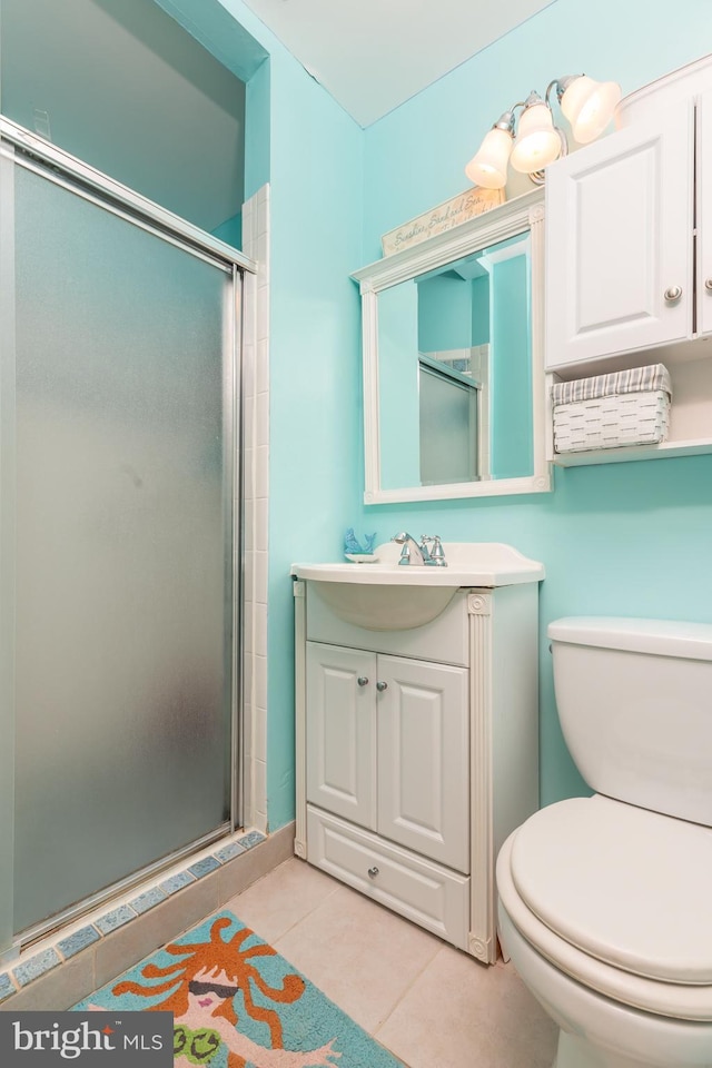 bathroom featuring a shower with shower door, toilet, vanity, and tile patterned flooring