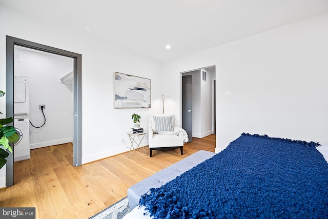 bedroom with hardwood / wood-style flooring and stacked washer / drying machine