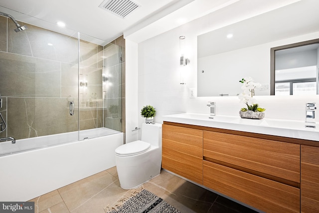 full bathroom with backsplash, vanity, shower / bath combination with glass door, tile patterned flooring, and toilet