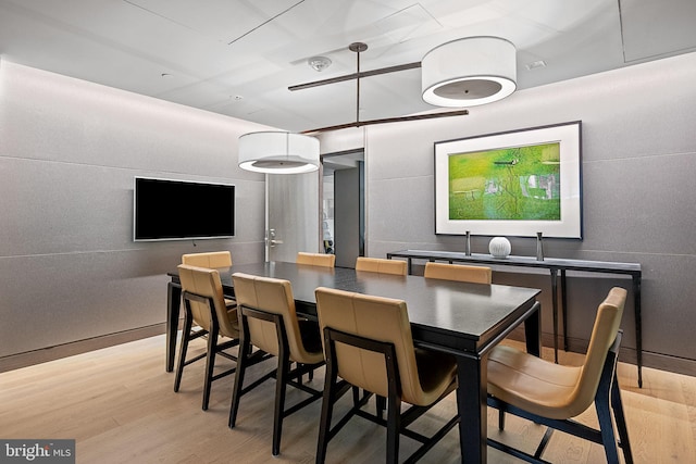 dining space featuring light wood-type flooring and tile walls