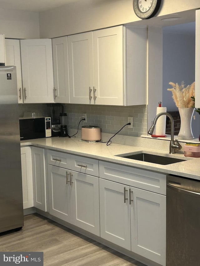 kitchen featuring backsplash, white cabinetry, sink, and appliances with stainless steel finishes