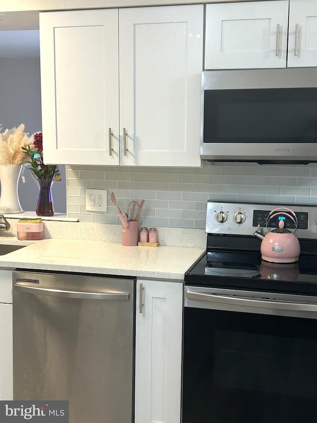 kitchen with appliances with stainless steel finishes, tasteful backsplash, and white cabinetry