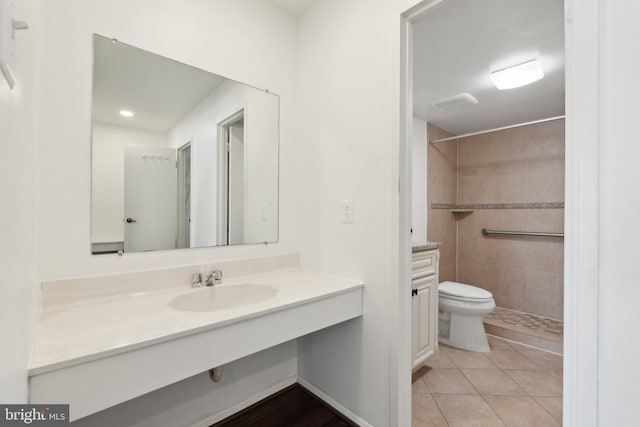 bathroom featuring toilet, a tile shower, tile patterned floors, and vanity