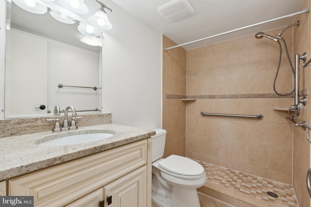 bathroom with tiled shower, tile patterned floors, vanity, and toilet