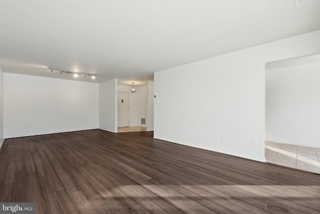 empty room featuring track lighting and hardwood / wood-style flooring