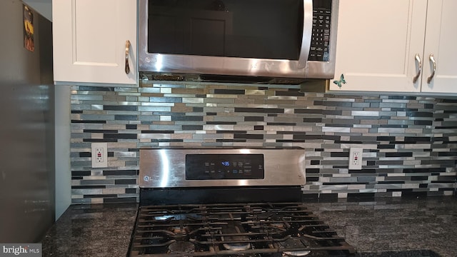 room details featuring backsplash, dark stone countertops, white cabinetry, and appliances with stainless steel finishes