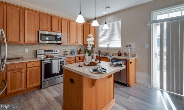 kitchen with a kitchen island, a breakfast bar, decorative light fixtures, decorative backsplash, and stainless steel appliances