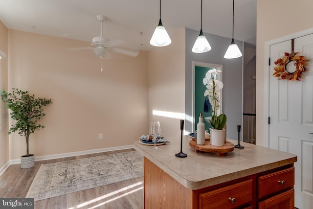 kitchen featuring ceiling fan, decorative light fixtures, a kitchen island, and light wood-type flooring