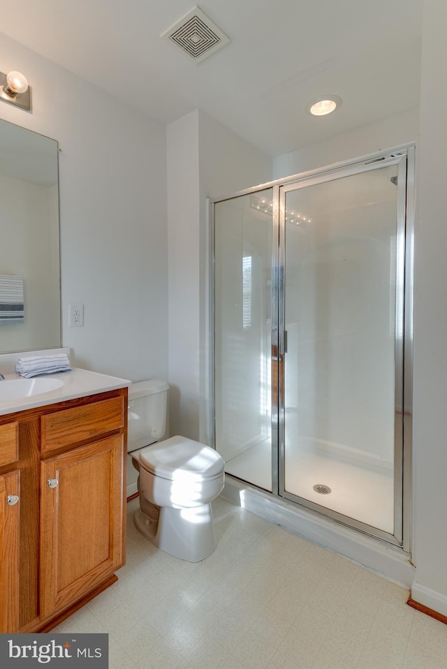 bathroom featuring vanity, toilet, and a shower with door