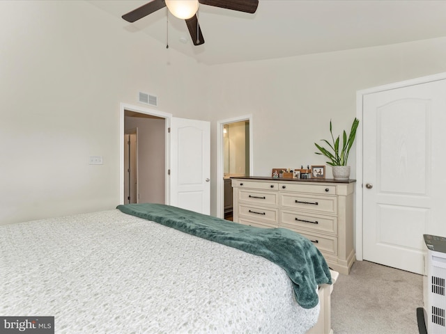 carpeted bedroom with ensuite bathroom, vaulted ceiling, and ceiling fan