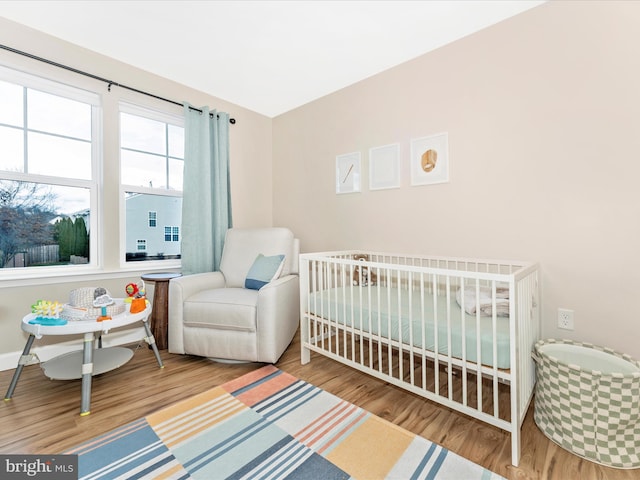 bedroom featuring a nursery area and hardwood / wood-style flooring