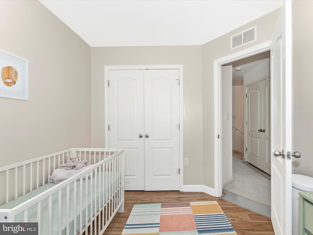 unfurnished bedroom with a crib, hardwood / wood-style flooring, and a closet