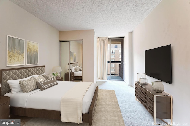 bedroom with access to exterior, a textured ceiling, light colored carpet, and a wall of windows