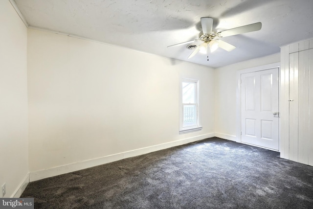 empty room with dark colored carpet and ceiling fan