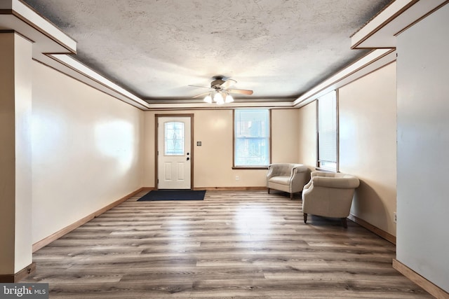 unfurnished room featuring ceiling fan, ornamental molding, a textured ceiling, and hardwood / wood-style flooring