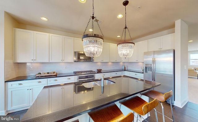 kitchen featuring stainless steel appliances, white cabinets, and hanging light fixtures