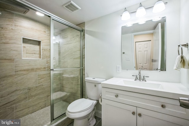 bathroom featuring toilet, a shower with shower door, and vanity