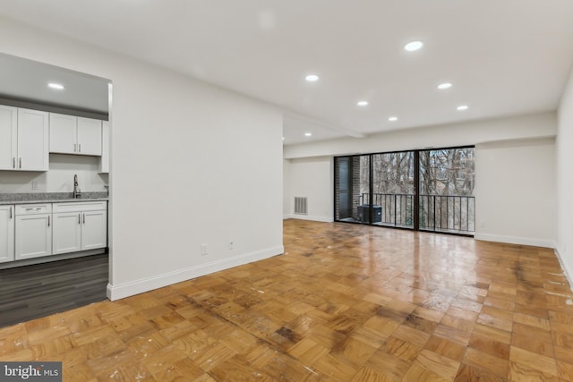 unfurnished living room featuring sink and light parquet floors