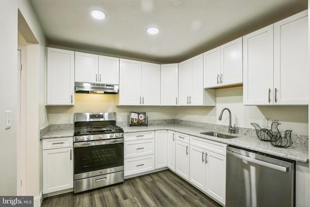 kitchen with appliances with stainless steel finishes, dark wood-type flooring, light stone countertops, white cabinets, and sink