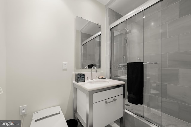 bathroom featuring vanity, toilet, and a shower with shower door