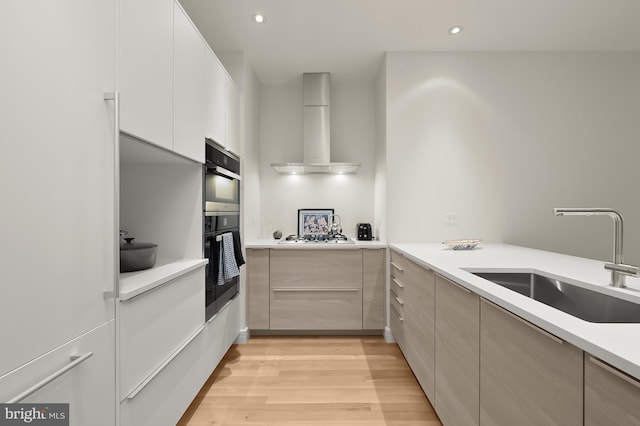 kitchen featuring sink, gas cooktop, ventilation hood, black double oven, and light hardwood / wood-style floors