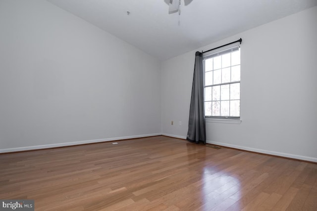 empty room with light hardwood / wood-style floors, a wealth of natural light, and lofted ceiling