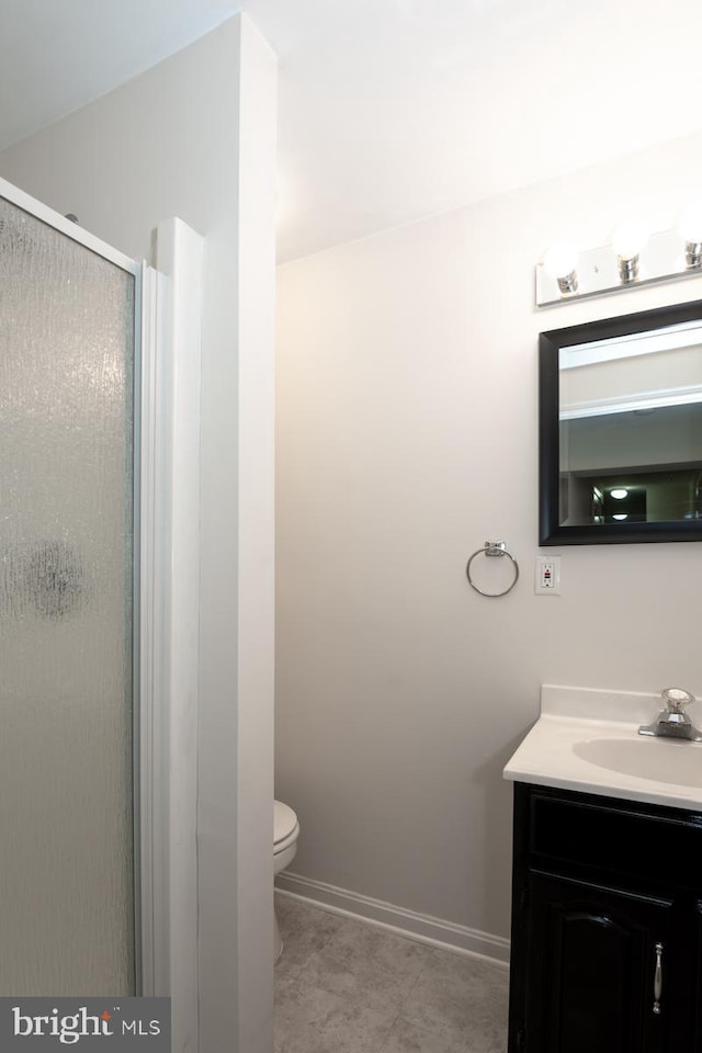 bathroom featuring tile patterned floors, vanity, toilet, and a shower with door