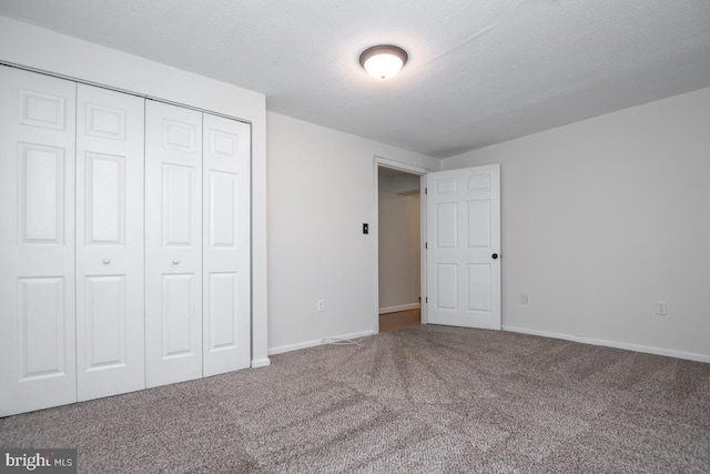 unfurnished bedroom featuring carpet flooring, a textured ceiling, and a closet