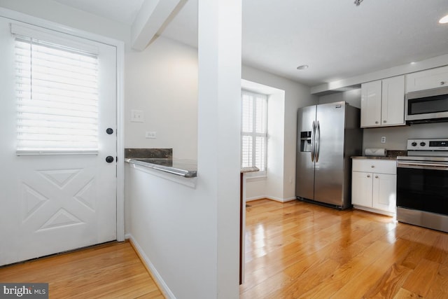 kitchen featuring white cabinets, appliances with stainless steel finishes, and light hardwood / wood-style flooring