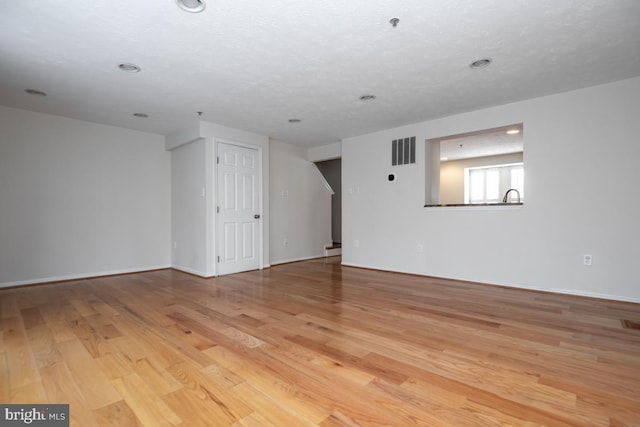 spare room with light wood-type flooring and a textured ceiling