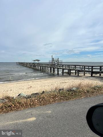 view of dock with a water view and a beach view