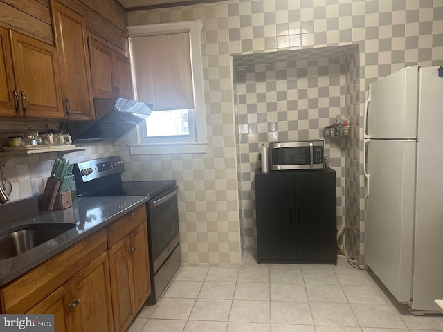 kitchen featuring stainless steel appliances, extractor fan, sink, light tile patterned floors, and dark stone countertops