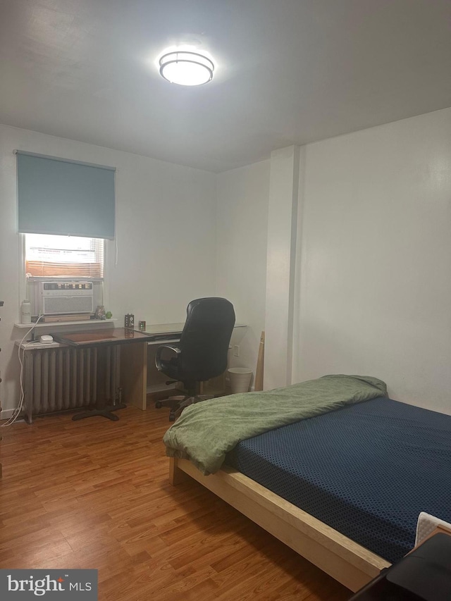 bedroom with cooling unit, wood-type flooring, and radiator