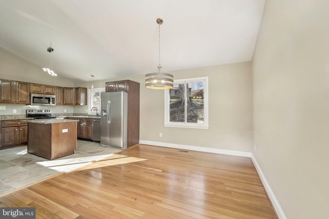 kitchen featuring a center island, hanging light fixtures, a notable chandelier, appliances with stainless steel finishes, and light wood-type flooring