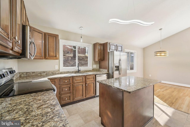 kitchen featuring a center island, sink, vaulted ceiling, appliances with stainless steel finishes, and decorative light fixtures