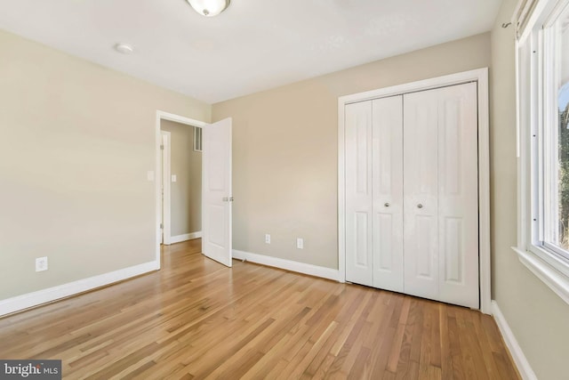 unfurnished bedroom with light hardwood / wood-style flooring and a closet