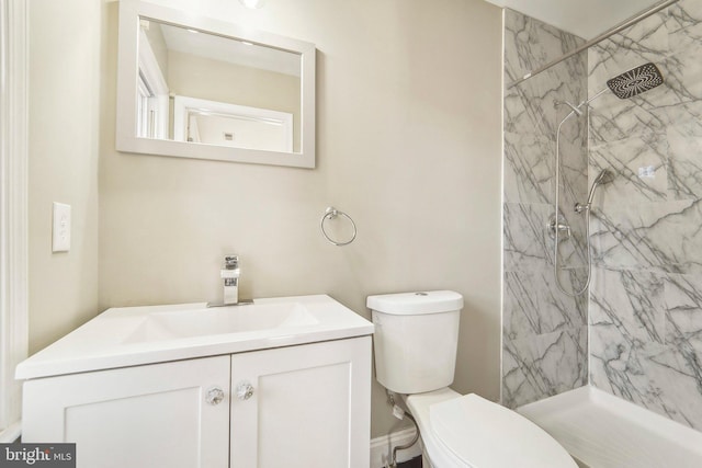 bathroom with a tile shower, vanity, and toilet