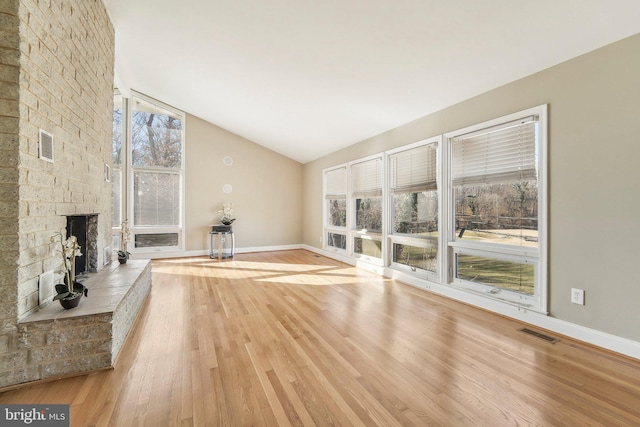 unfurnished living room with a fireplace, light hardwood / wood-style floors, and lofted ceiling