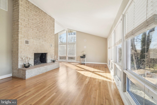 unfurnished living room featuring a fireplace, light wood-type flooring, and high vaulted ceiling