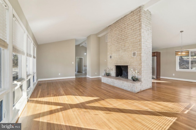 unfurnished living room with a brick fireplace, beamed ceiling, high vaulted ceiling, a notable chandelier, and wood-type flooring