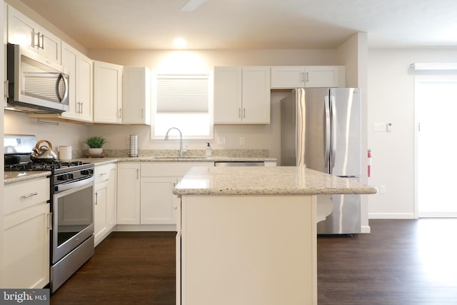 kitchen featuring light stone counters, a center island, sink, and stainless steel appliances