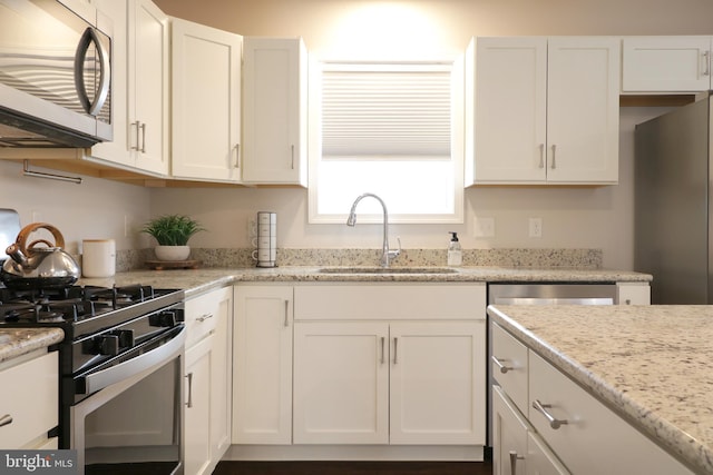 kitchen featuring white cabinets, light stone counters, sink, and appliances with stainless steel finishes