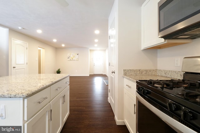 kitchen featuring white cabinetry, light stone counters, dark hardwood / wood-style floors, range with gas stovetop, and a kitchen island