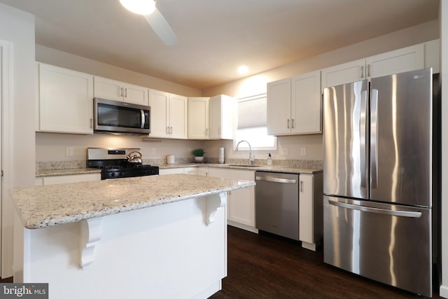 kitchen featuring a breakfast bar, stainless steel appliances, sink, white cabinets, and a center island