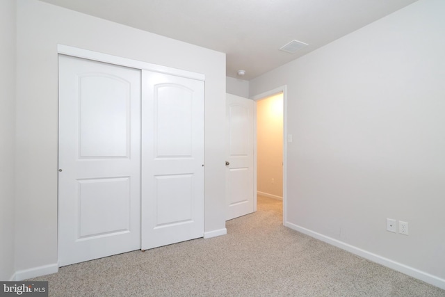 unfurnished bedroom with light carpet and a closet