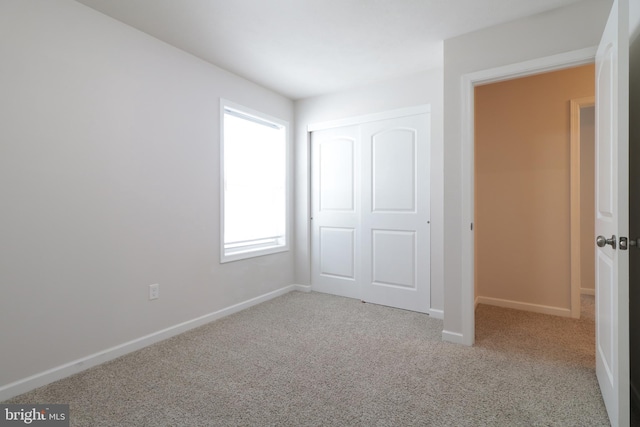 unfurnished bedroom featuring light carpet and a closet