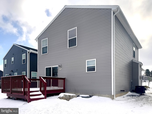 snow covered back of property featuring a deck