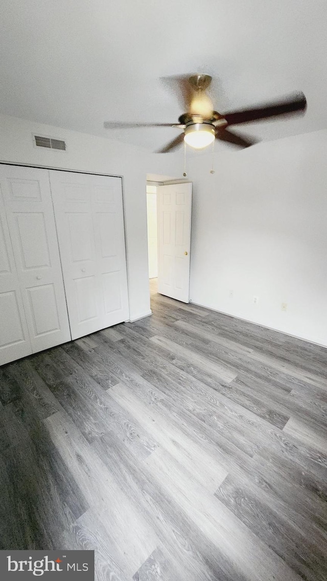 unfurnished bedroom featuring ceiling fan, wood-type flooring, and a closet