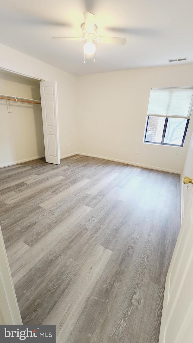 unfurnished bedroom with ceiling fan, hardwood / wood-style flooring, and a closet