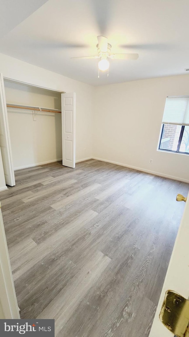 unfurnished bedroom featuring ceiling fan, a closet, and hardwood / wood-style floors